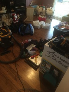 Messy living room with a toilet in a box and paint rollers, etc. 